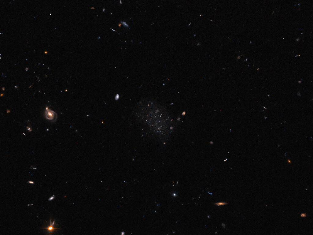 Peek into cosmic depths: Can you spot a dwarf galaxy in the middle of this Hubble image?